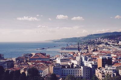 High angle view of cityscape by sea against sky