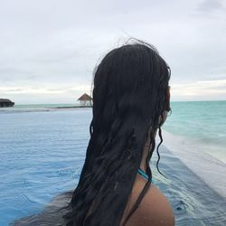 Rear view of woman on beach against sky