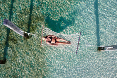 Attractive woman relaxing on a hammock over the water. air view.