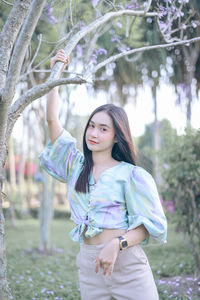 Young woman standing against trees