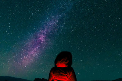 Rear view of woman standing against star field at night