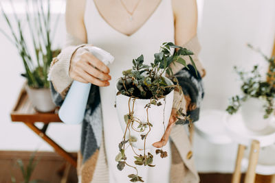 Girl florist gardener watering and spraying potted plants and flowers at home, take care of plants