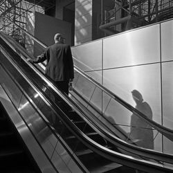 Rear view of man standing on escalator