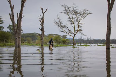 Man standing by lake against sky