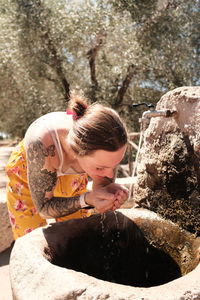 Rear view of woman drinking from fountain