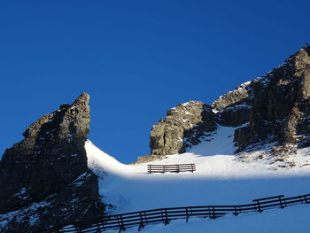 Low angle view of snow covered mountain against clear blue sky