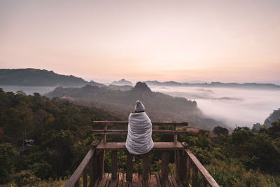 Rear view of man on mountain against sky during sunset