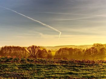 Vapor trail on landscape against sky