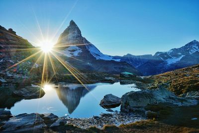 Scenic view of lake and mountains against clear blue sky