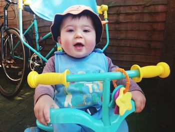 Portrait of cute baby boy sitting in tricycle