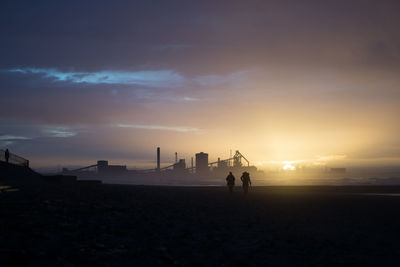 Silhouette people at beach against sky during sunset