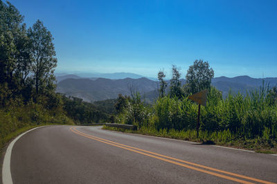 Road by trees against sky