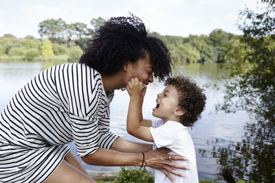 Mother and daughter at riverbank against trees