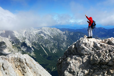 Rear view of man standing on rock against sky