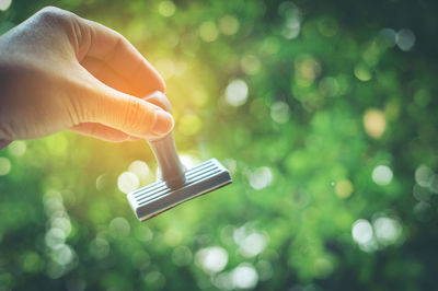 Close-up of hand holding rubber stamp against trees