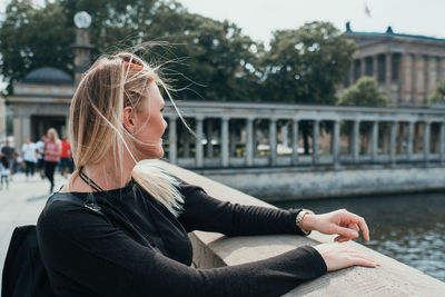 Young woman sitting on bridge over water