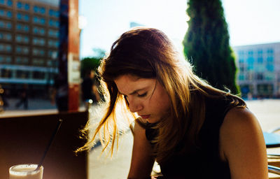 Close-up of young woman with iced coffee on sunny day