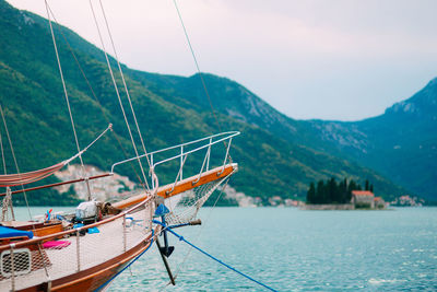 Sailboat on sea by mountains against sky