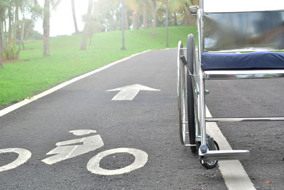 Empty wheelchair by field on road with markings