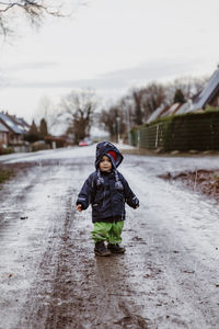 Boy on snow covered landscape against sky