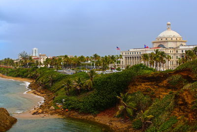 Government building in city by sea against sky