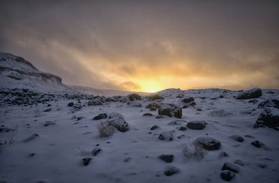 Scenic view of frozen landscape against sky during sunset