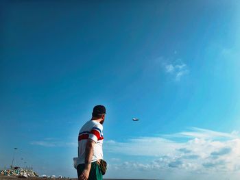 Low angle view of boy standing against sky