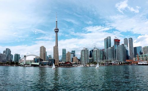 City at waterfront against cloudy sky