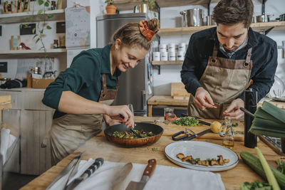 Chefs garnishing plate while standing in kitchen