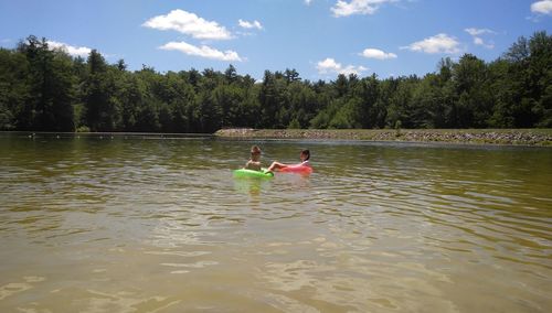 People sitting on lake against sky