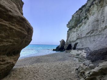 Rock formations on beach against clear sky