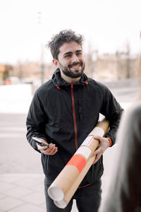 Smiling young delivery man delivering package