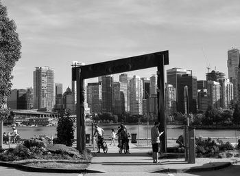 People by buildings in city against sky. vancouver under the arch, from stanley park.