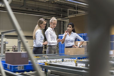 Three women discussing at conveyor belt in factory