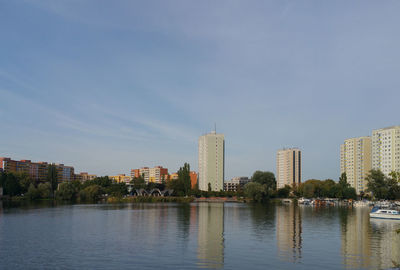 Buildings by river against sky in city