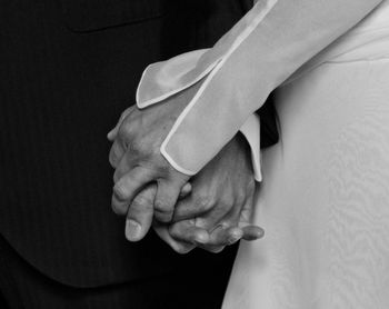 Close-up of couple holding hands at wedding