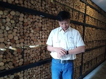 Full length of man standing by stack of wood