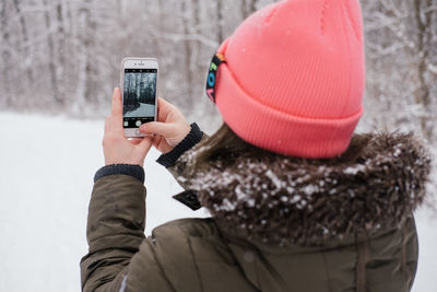 Midsection of person photographing mobile phone in snow