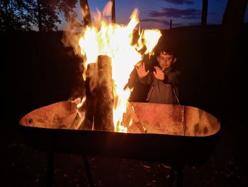 Boy standing by bonfire at night