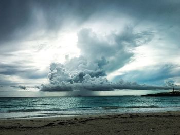 Scenic view of beach against cloudy sky