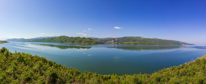 Scenic view of lake and mountains against blue sky