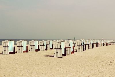 Hooded beach chairs against sky on sunny day