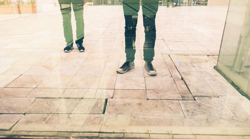 Low section of people standing against glass building