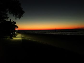 Silhouette man on beach against sky during sunset