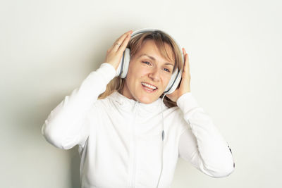 Cheerful woman listening music against white background