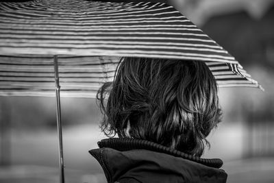 Rear view of woman holding umbrella outdoors