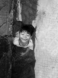 Portrait of smiling girl standing on tree trunk