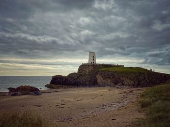 Lighthouse amidst sea and buildings against sky