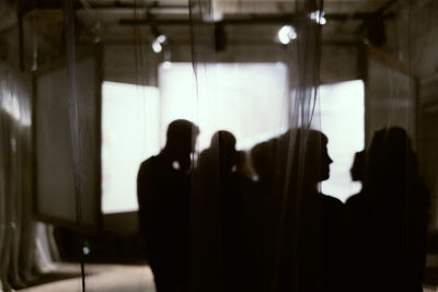 Silhouette people standing against illuminated lighting equipment in studio