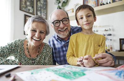 Portrait of happy grandparents with grandson at home